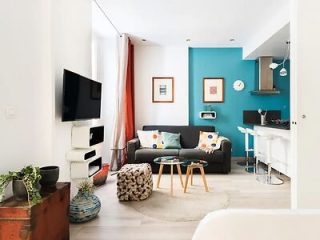 Bright and airy studio apartment with a teal accent wall, modern furniture, and pops of color