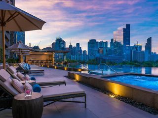 Twilight at a rooftop lounge area with a pool, showcasing a panoramic view of Manila's skyline, elegant outdoor furniture, and ambient lighting