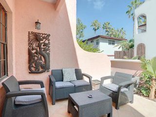 Outdoor patio area with wicker seating and a center table, adorned with a large metal seahorse wall sculpture, capturing a tranquil suburban vibe.