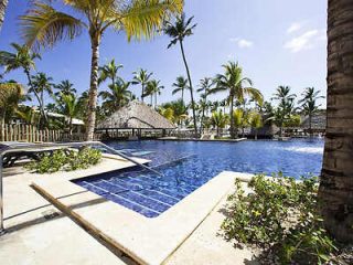 Idyllic resort swimming pool surrounded by palm trees under a sunny sky, reflecting the essence of a tropical getaway.