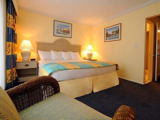 Cozy bedroom with a large bed featuring a light-colored headboard and bedding, flanked by wicker nightstands and decorative lamps.