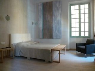 Minimalist bedroom with a large bed, abstract wall art, and neutral tones