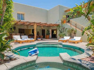 Secluded courtyard with a private pool, lounge chairs, and lush greenery in a luxury home setting.