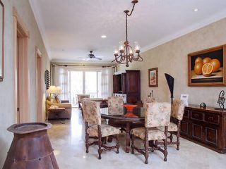 Spacious dining room in an upscale residence, with a traditional dining set, ornate chandelier, and a sideboard displaying decorative items.