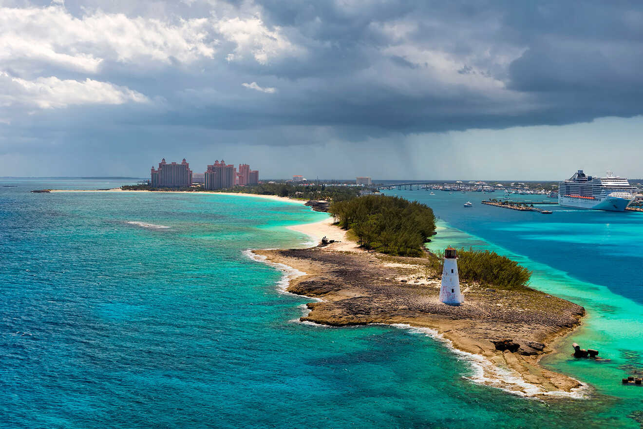 Scenic coastline featuring a white lighthouse on a rocky outcrop, with dark storm clouds gathering over a distant resort complex.