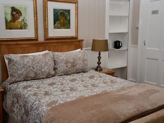 Cozy bedroom with lace-covered bedspread and classic portrait art