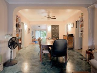 Spacious dining and living area with an open-plan design, featuring a large dining table, office chair, and a homely kitchen in the background.