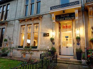 Warmly lit entrance of Seton Guest House with planters and a welcoming sign