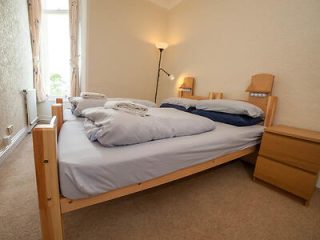 Simple bedroom with pine bed and neutral bedding by a window