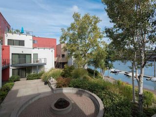 Waterfront apartment complex with a seating area and a view of moored boats