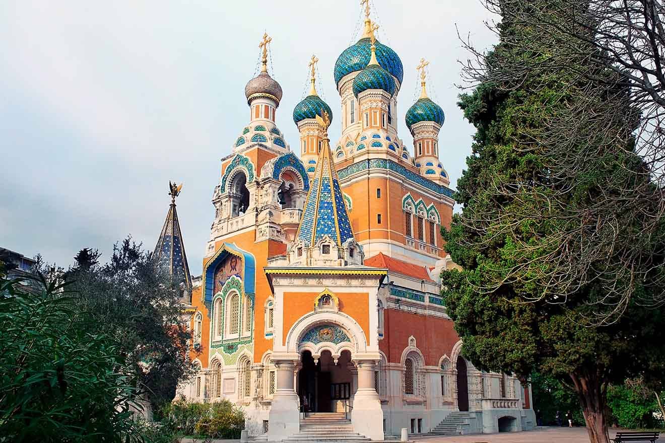The striking Russian Orthodox Cathedral in Nice with its colorful onion domes and elaborate architecture, standing out against the greenery and cloudy skies