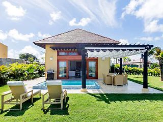 Private villa with a shaded patio area and sun loungers on a lush lawn, showcasing a serene holiday retreat.