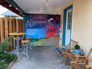 Outdoor patio with a vibrant mural titled 'Strange Adventures'