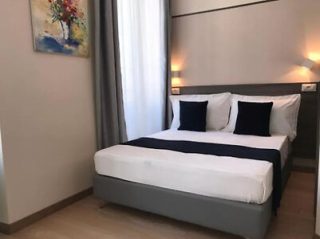 Simple yet elegant bedroom with a large double bed with navy blue accents, soft lighting, and a vibrant painting above the headrest