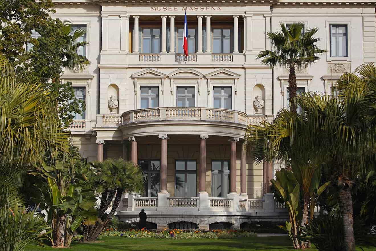 The ornate façade of Musée Masséna in Nice, surrounded by lush palm trees and manicured gardens, reflecting the city's rich cultural heritage.