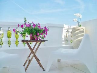 Quaint rooftop terrace with white sculptural furniture and hanging plants