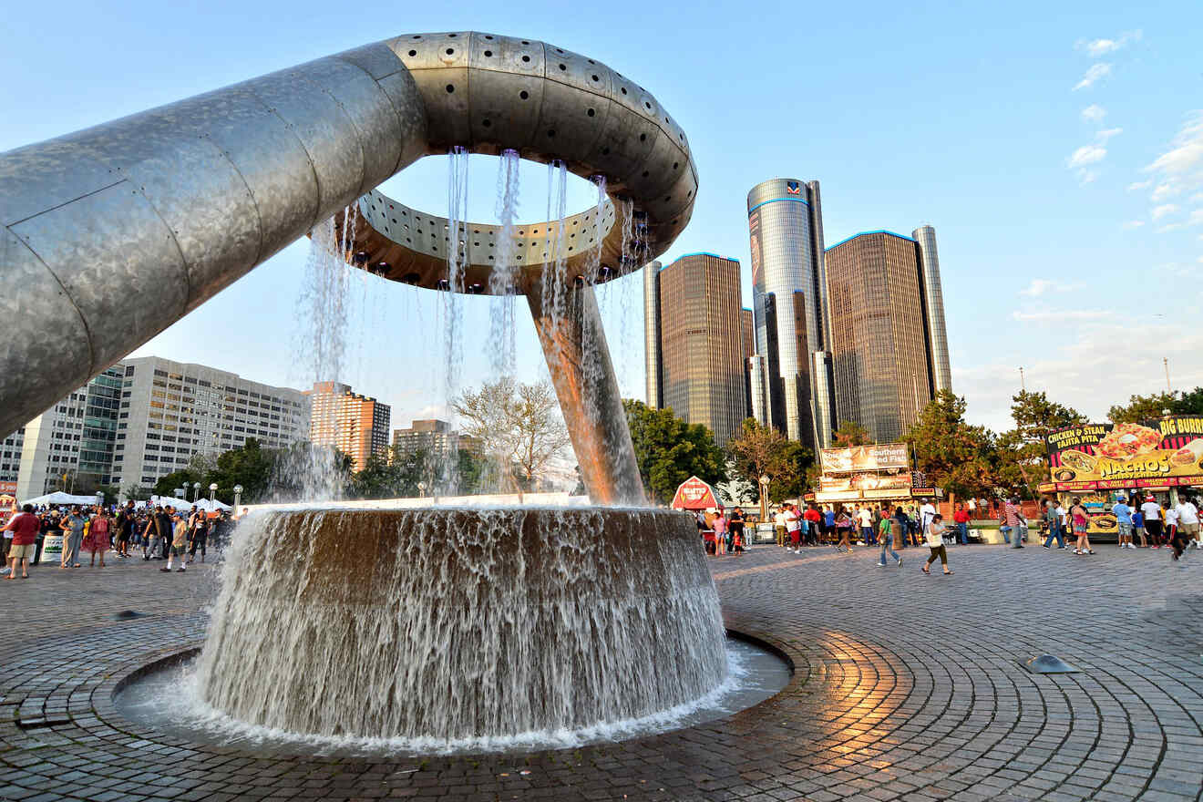 People gathering around the iconic circular water fountain at Hart Plaza with the GM Renaissance Center towering in the background in Detroit