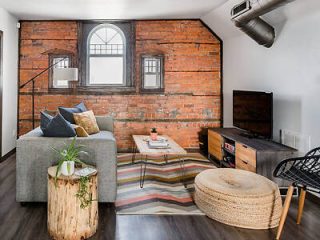 Cozy living space with exposed brick walls, a gray sectional sofa and a wooden coffee table