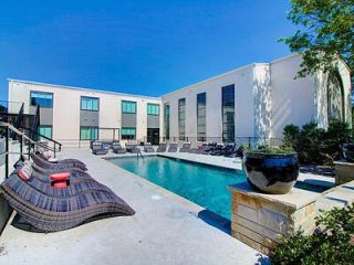 Contemporary pool area with stylish loungers and a large fountain feature, providing a luxurious outdoor setting.