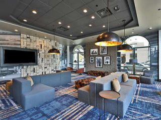 Stylish hotel lounge with modern furniture, patterned carpets, and a large TV, designed for relaxation and socializing.