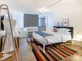 Modern and bright hotel room with a queen-sized bed with a geometric-patterned sheets