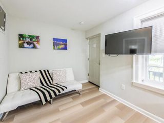 A minimalist modern living room with a sleek white futon against a backdrop of vibrant cityscape artwork.