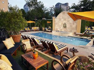 Elegant outdoor poolside seating area with yellow umbrellas and a tranquil water feature, evoking a sense of luxury urban leisure.