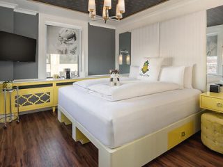 A hotel room with a yellow bed and yellow accents.