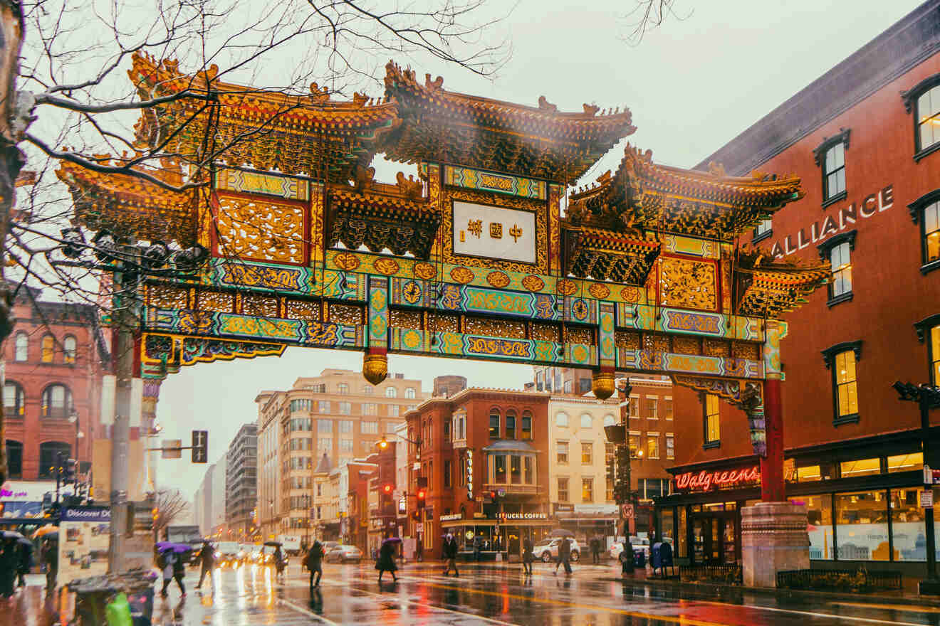 The iconic Friendship Archway in Washington D.C.'s Chinatown with pedestrians and city life bustling beneath, on a rainy evening.
