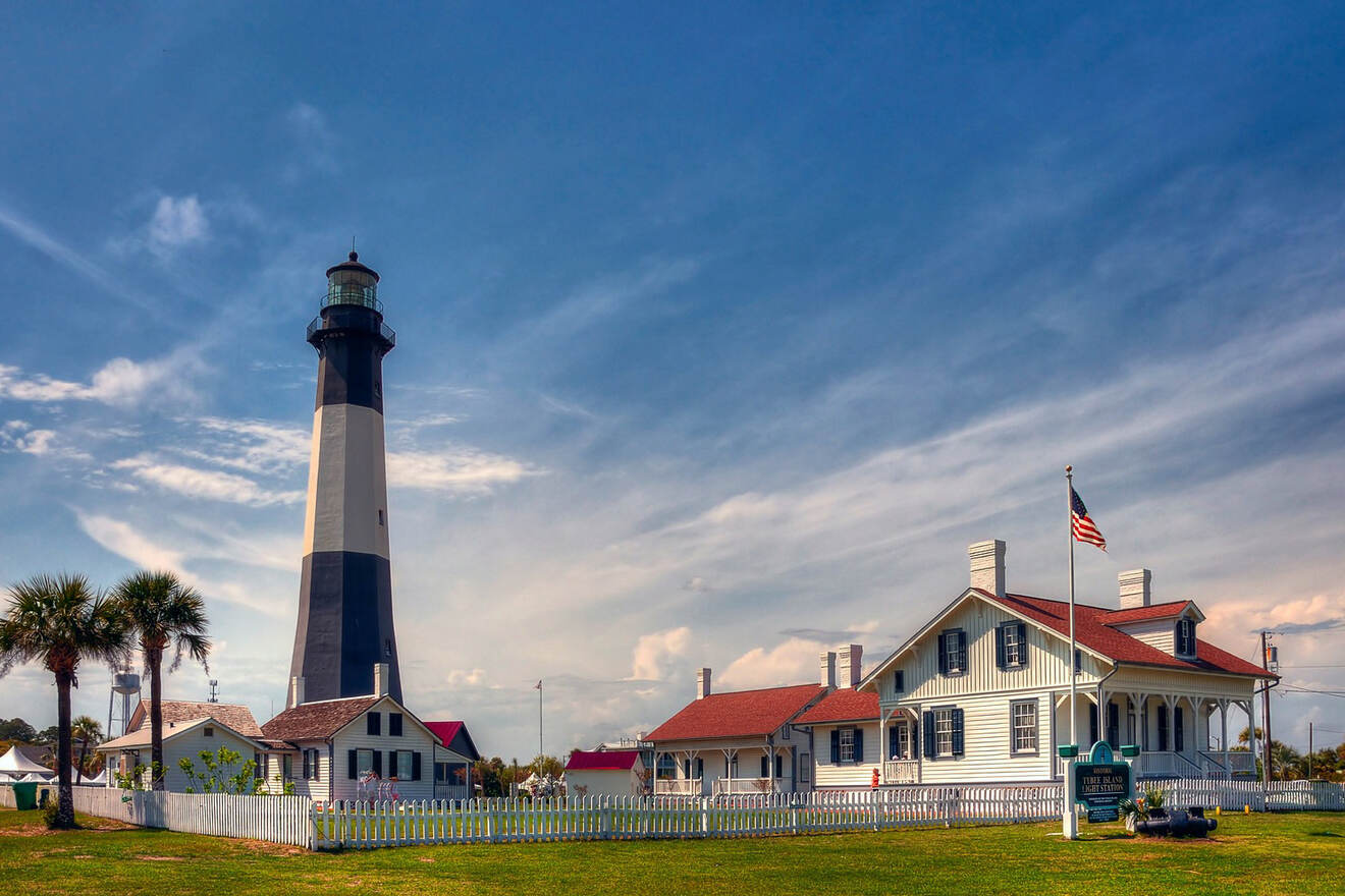 The Tybee Island Light Station and Museum, a historic lighthouse with black and white stripes, under a blue sky with scattered clouds.