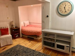 A small room with a bed and a clock on the wall.