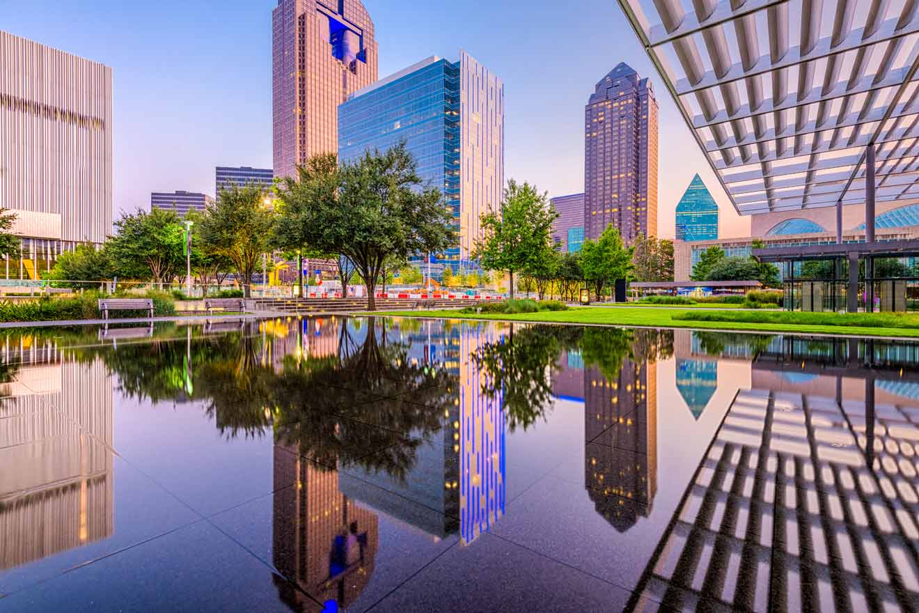 Reflective pool in a modern Dallas park at dawn with skyscrapers and architecture mirrored on the water's surface.
