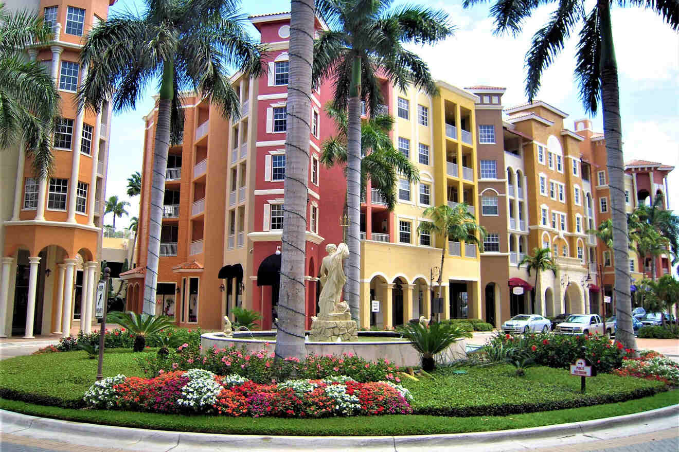 Colorful Mediterranean-style building with archways and a central statue, surrounded by lush gardens under palm trees, exemplifying Naples’ vibrant architecture.