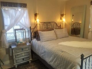 Inviting bedroom with a classic iron bed frame, soft white linens, and mirrored bedside table, creating a romantic and vintage atmosphere