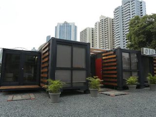 Innovative container housing with several black and orange cargo containers set up as living spaces in an urban outdoor setting