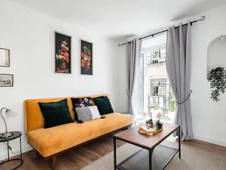 Elegant, simple living room with a yellow sofa, gray curtains, and decorative wall art in a Lisbon apartment