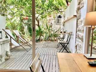 Tranquil outdoor patio with wooden decking, comfortable chairs, and lush potted plants creating a serene urban oasis