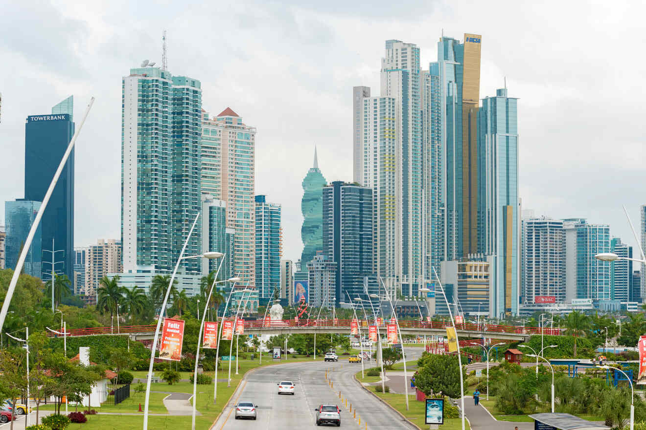 road avenue in Panama City with rows of palm trees and modern high-rise buildings, leading towards a monument and a cloudy sky backdrop