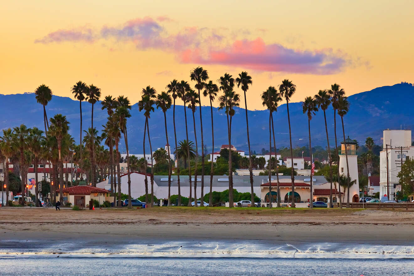 A Santa Barbara beach scene at sunset with silhouetted palm trees against a colorful sky, reflecting the serene end to a day in this coastal paradise