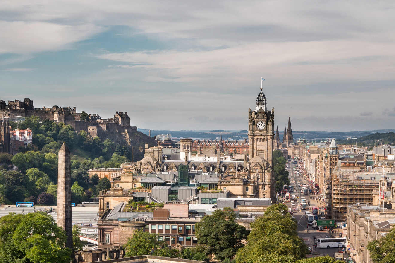 A panoramic view of Edinburgh with the Castle and Balmoral Clock Tower standing prominent against a backdrop of blue skies and scattered clouds.