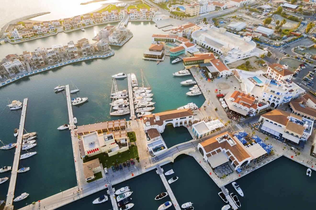 Aerial view of a bustling marina in Cyprus with docked yachts and surrounding residential buildings, highlighting the luxury seaside lifestyle