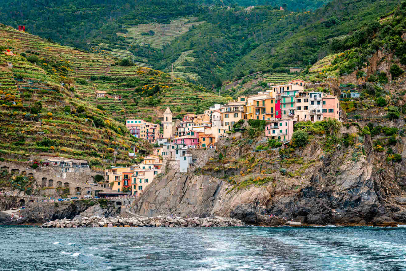 Scenic view of Manarola village perched on rocky cliffs with colorful houses and vineyards, highlighting the beauty of Cinque Terre