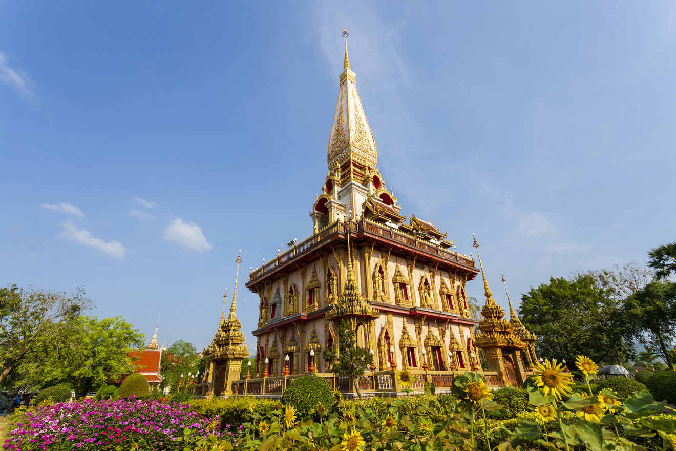 Majestic view of a Thai Buddhist temple with an intricate golden spire, surrounded by vibrant gardens with sunflowers under a clear blue sky, reflecting Thailand's rich cultural heritage.

