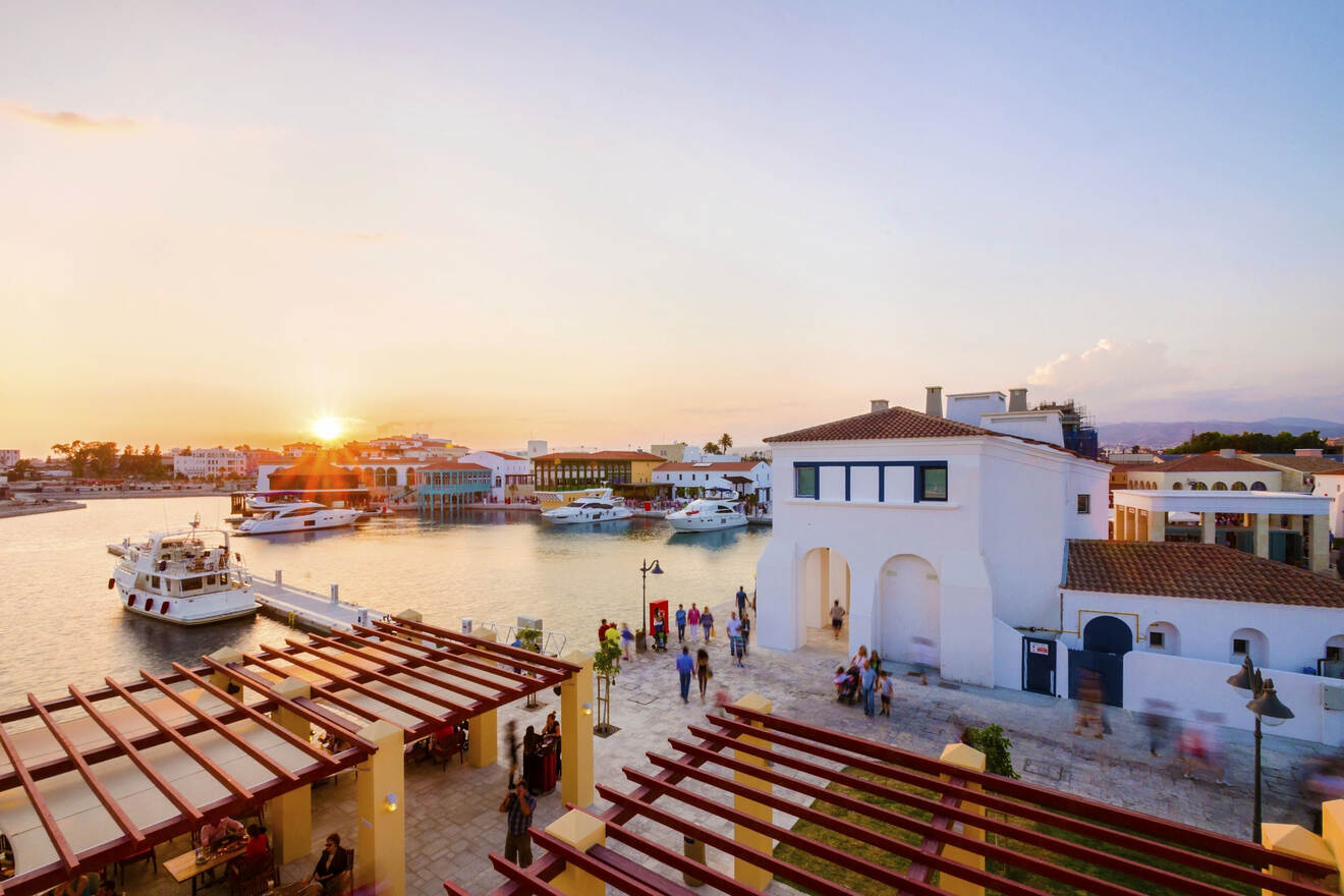 Sunset view over a bustling waterfront promenade in Cyprus with dining patrons and moored boats, capturing the lively spirit of a coastal town at dusk