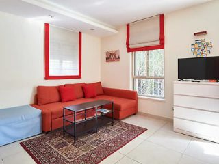 Living room with a red sofa, white tiled flooring, and a television set against a minimalist decor.