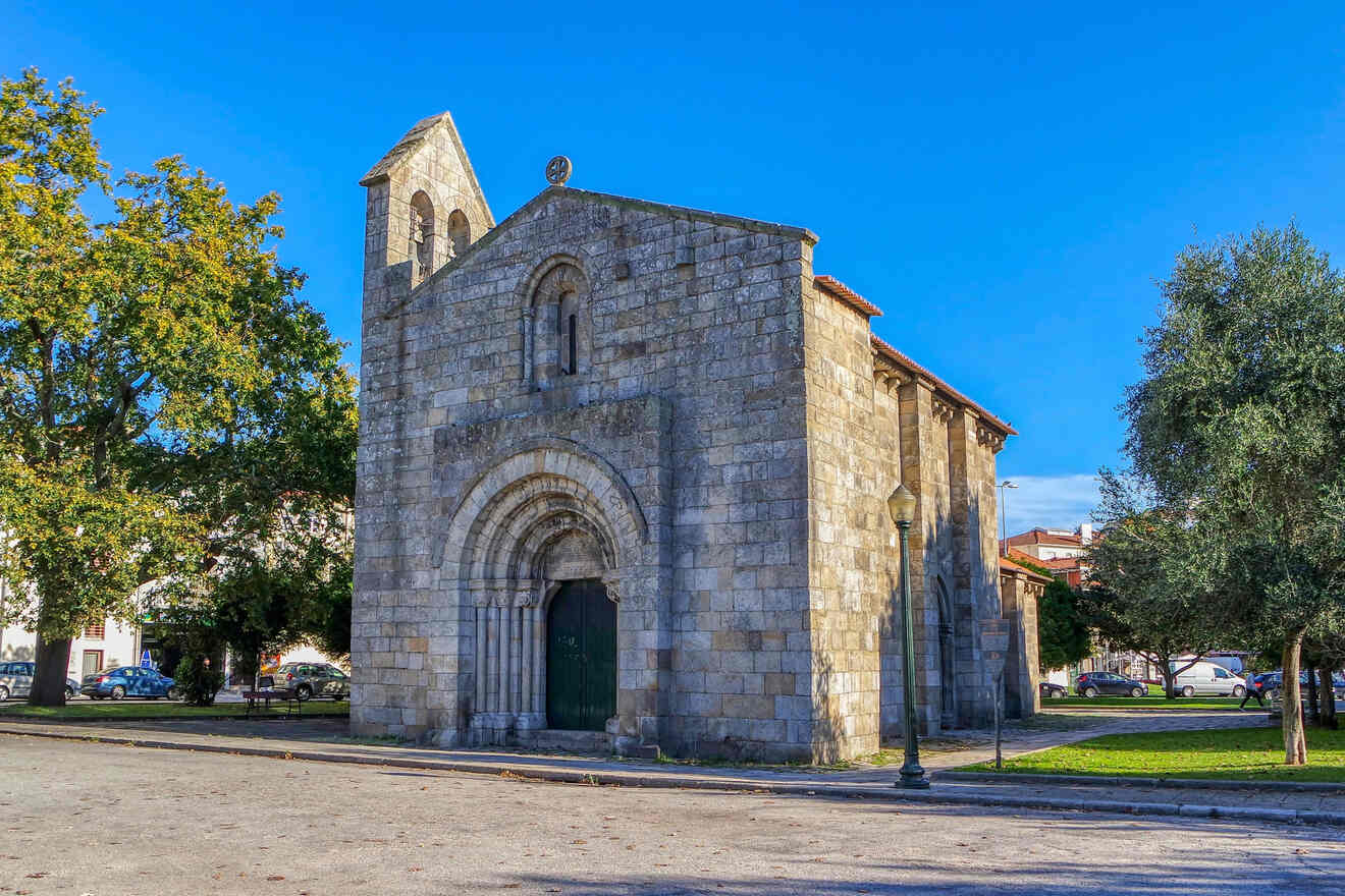 Ancient Romanesque church in Porto, Portugal, with a well-preserved stone facade and a towering belfry against a clear blue sky