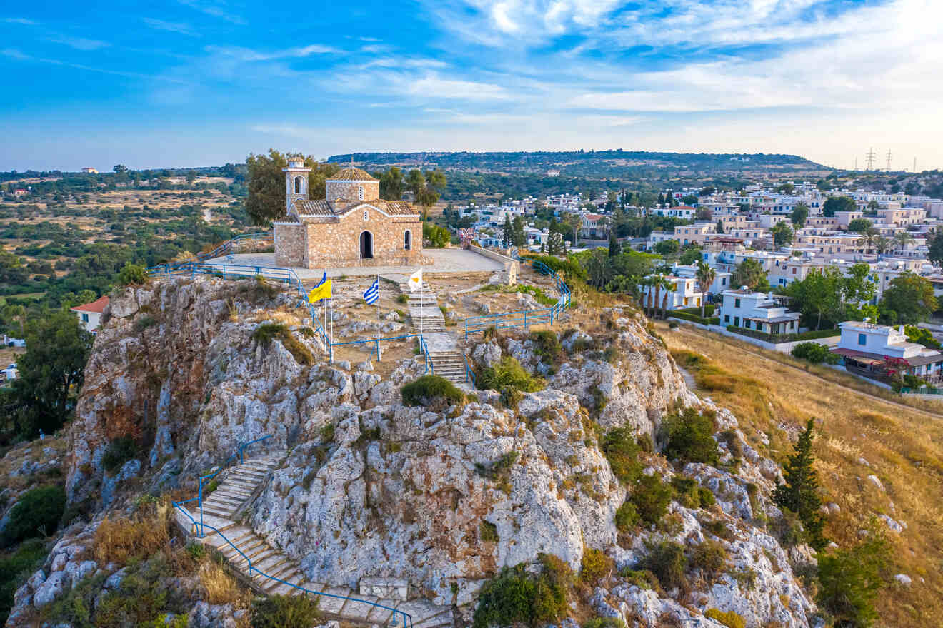 Majestic hilltop church with Greek flags in Protaras, Cyprus, overlooking a scenic village landscape, embodying cultural heritage and tranquility