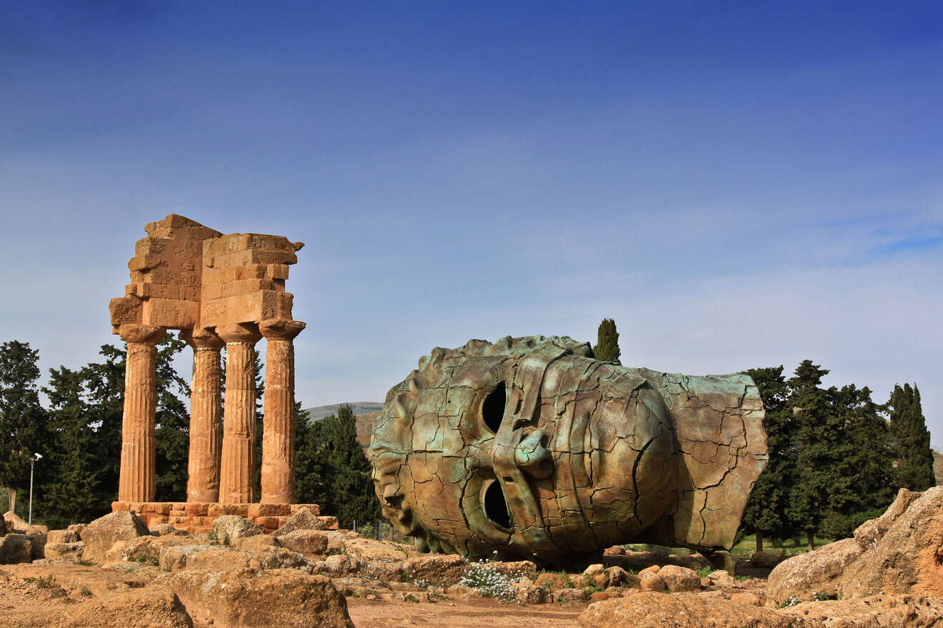 A statue of a head in the middle of a rocky area.