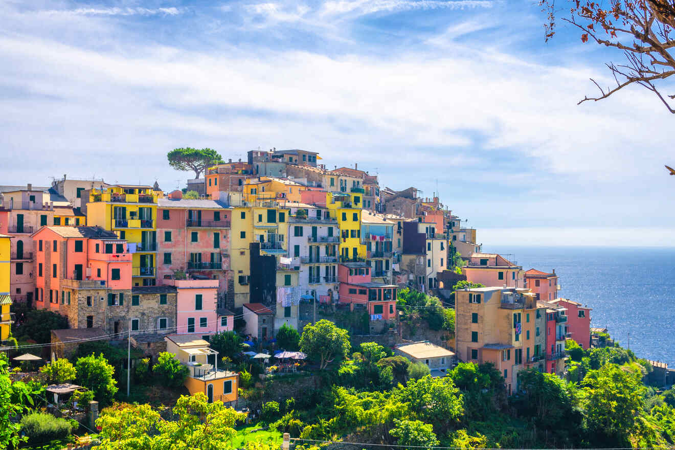 Elevated view of the colorful and stacked buildings of Cinque Terre, nestled in green hillsides and overlooking the tranquil sea