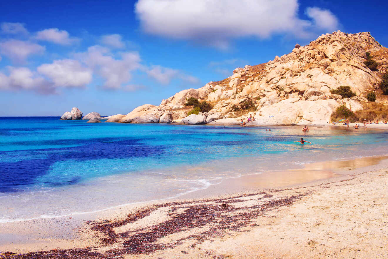 A serene beach with turquoise waters and rocky hills under a bright blue sky.